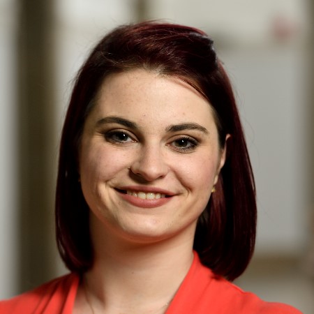 headshot of a young woman with short reddish hair and an orange blouse