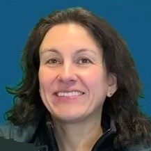 Woman with dark brown hair smiles against blue background