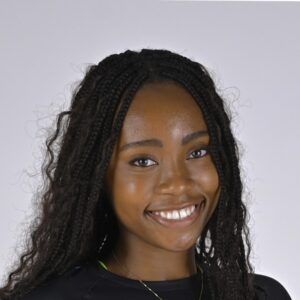 A young woman with curly black hair smiles warmly 